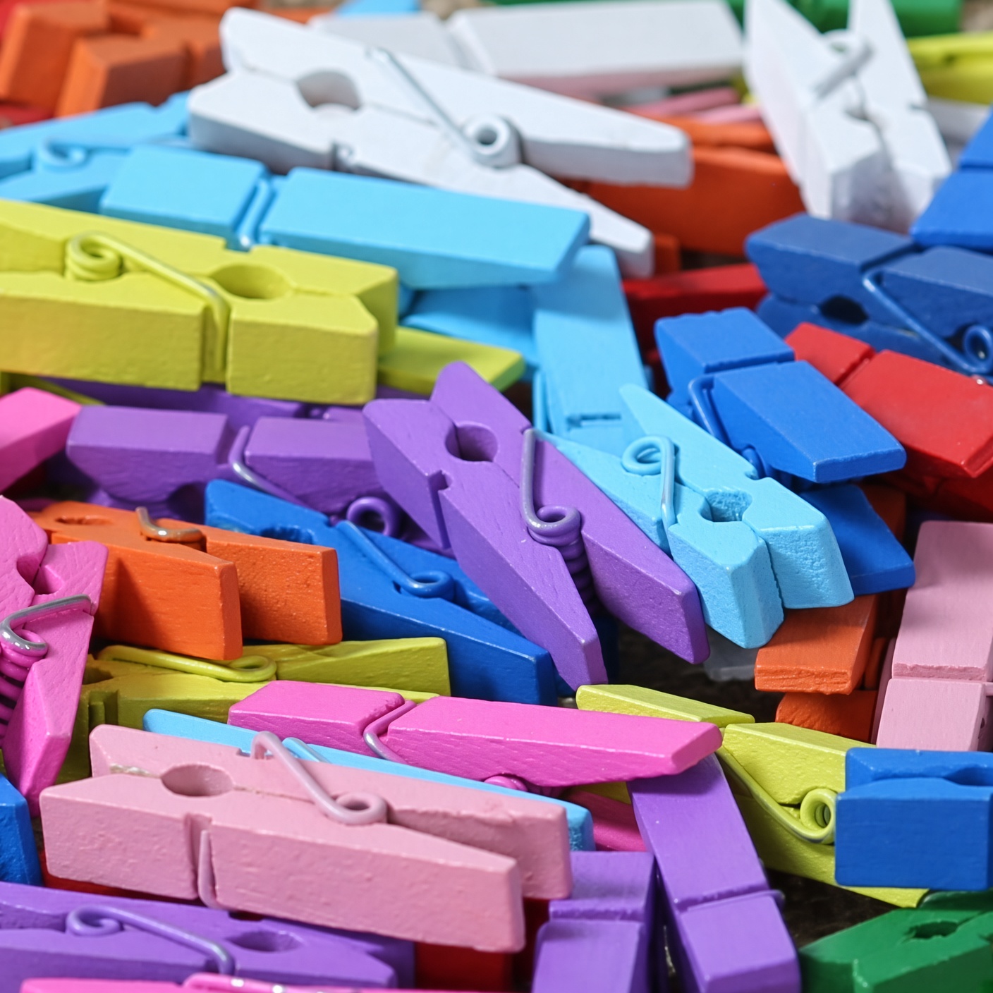 Viele bunte Holz-Dekoklammern in Pink, Blau, Lila, Grün, Orange und Weiß, 35 mm, lose aufgeschüttet in Nahaufnahme.